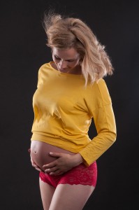Medium shot of Glowing pregnant mother looking at her belly pregnancy photography by Anais Chaine Auckland Photographer