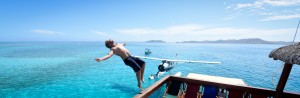 Backflip on boat's deck in the turquoise sea of Fiji