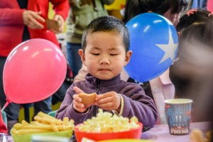 young asian boy eating a cake
