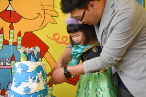 young girl cutting the cake with her father