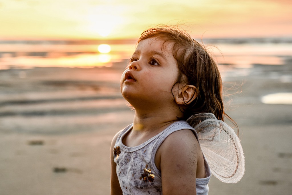 Baby Ainoha in tiny wings against sunset on the beach