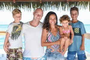 This beautiful family smiles at the camera against the turquoise blue sea aboard Cloud 9 Fiji