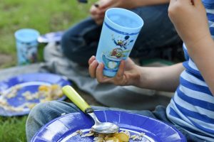Blue plastic glass in the hand of a young boy for pic nic