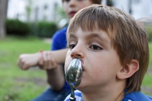young boy with a spoon on his mouth thinking