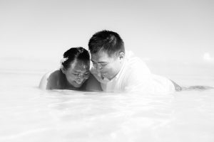 black and white photograph of a couple lying down in the sea and looking at the water in Fiji by Anais Photography