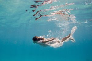 Underwater shot of a woman dressed in white in the sea
