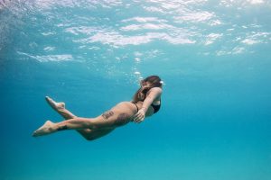Woman with tattoos swimming underwater