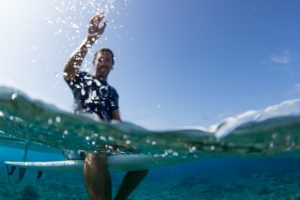 over under water photography with surfer splashing water at the photographer in Fiji by Anais Photography