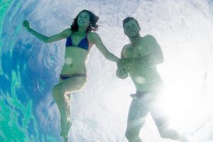 Couple underwater from underneath Cloud 9 in the Mamanuca islands in Fiji