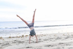 Young girl does cartwheels on the beach