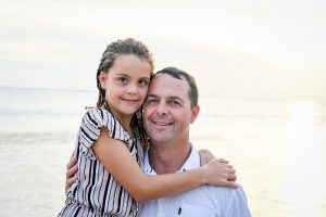Daddy and daughter hug on beach in Fiji