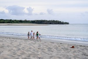 Wide shot of family strolling on beach in Fiji Natadola