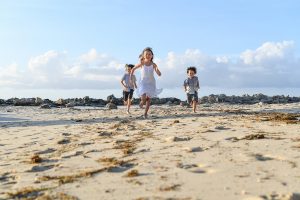 Wideshot of 3 cute kids running on the beach