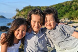 3 cute siblings do cute sidehug while posing on the beach during their family photoshoot