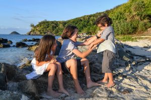 Brother tickles brother and sister laughs on the beach in family photo session Fiji