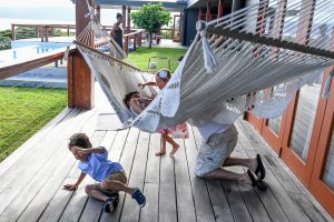 Triplets and dad play on hammock during Fiji family vacation