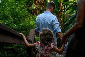 Dad and daughter walk on bridge into tropical forest during family holiday in Fiji