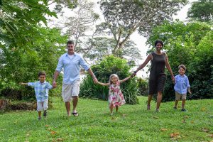 Mixed race family hold hands while walking on lawn in Fiji family vacation