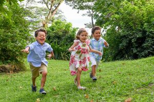 Triplets run on green lawn during Fiji family vacation
