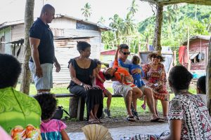Family seated at traditional Fiji gathering during family vacation