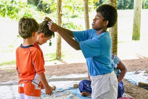 Fiji woman puts traditional Fiji necklace on boy