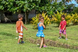 Triplets play in the grass in Fiji family vacation