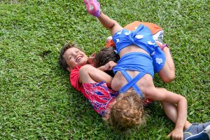 Cute Triplets play in grass during Fiji family vacation