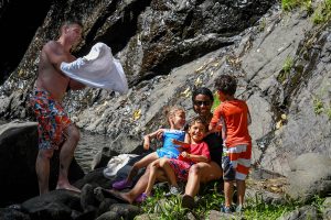 Family sit against rock in Fiji family vacation