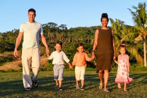 Family hold hands and walk towards the sunset in Fiji family photoshoot