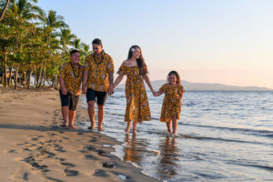 The family holds hands as they stroll into the sea at Fiji
