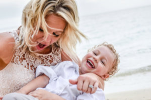 Mom tickles and laughs with son while on the beach