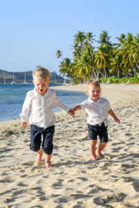 Brother and brother hand in hand in the sand on a Fiji beach on Plantation Island Resort