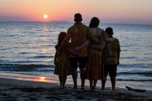 A silhouette befalls the family watching the stunning pink Fiji sunset