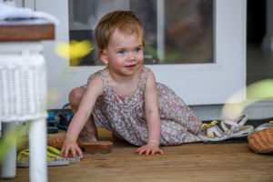 The cute ginger haired baby plays with sandals