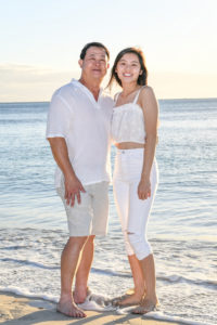 Asian father and daughter pose against the Fiji sea at sunset