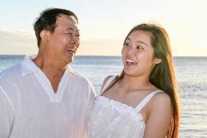 Asian father laughs with his daughter in the Fiji sunset