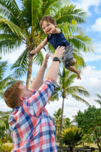 The baby is tossed up in the air against palm trees in Fiji