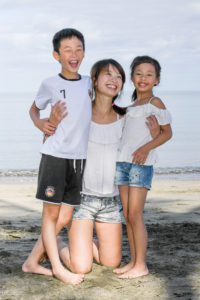 Cute asian family pose on the beach