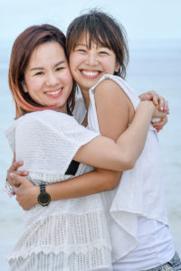 Asian sisters hug while at the beach at Natadola Fiji
