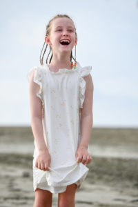 Cute caucasian girl in braids laughs on the beach