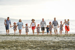 An extended family in matching outfits walks on the beach