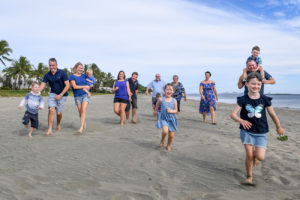 The extended family runs towards the camera while on Natadola beach