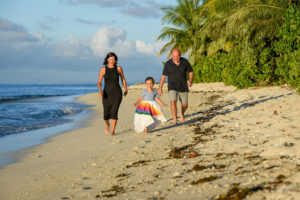Father, mother and daughter run on the beach