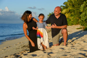 The family poses for photograph while kneeling in the sand