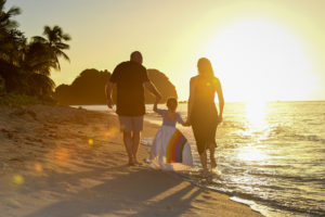 A fiery sun sets on the family as they stroll on the beach