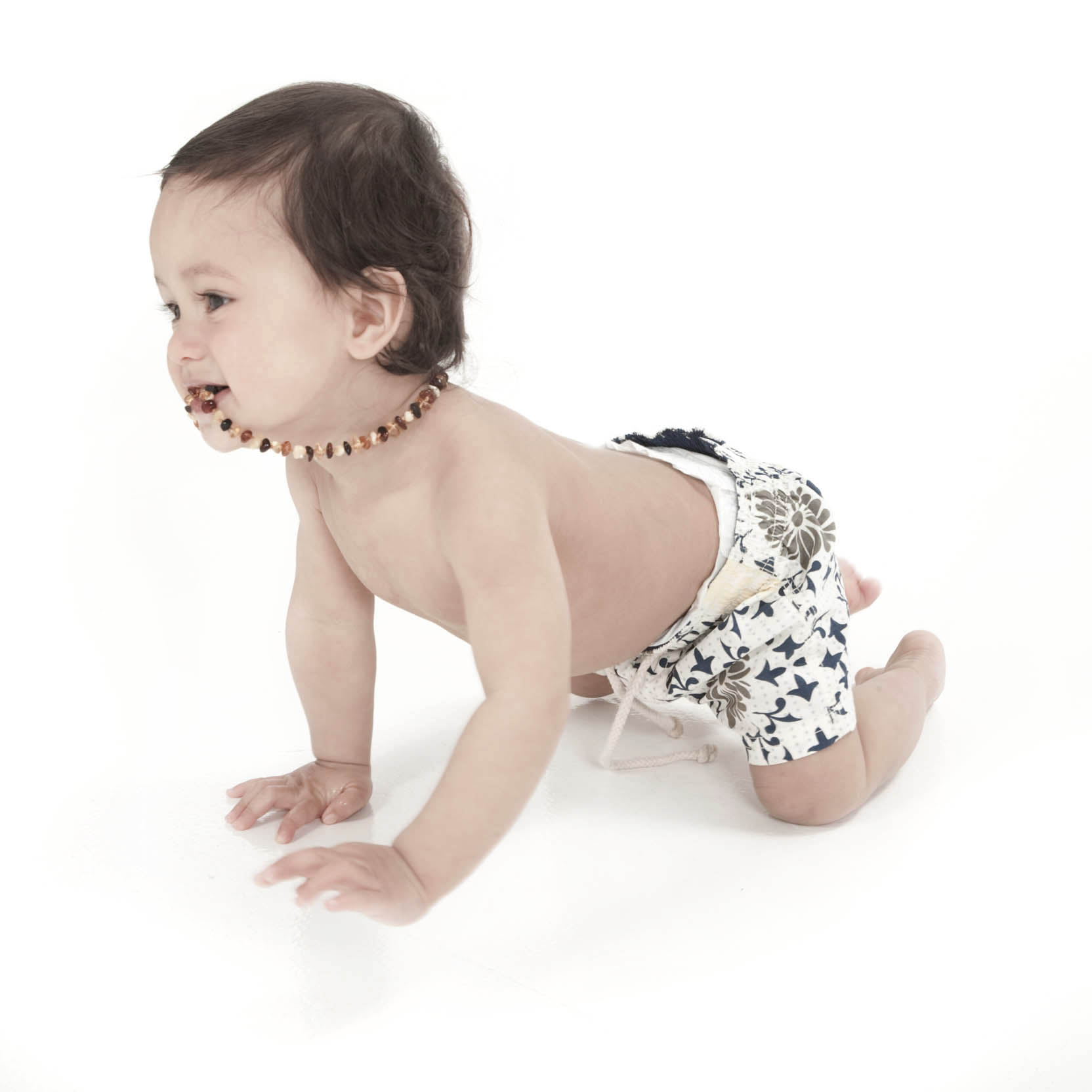 Toddler little boy crawling and chewing his necklace professional studio photography by Anais Chaine in Auckland Ponsonby New Zealand