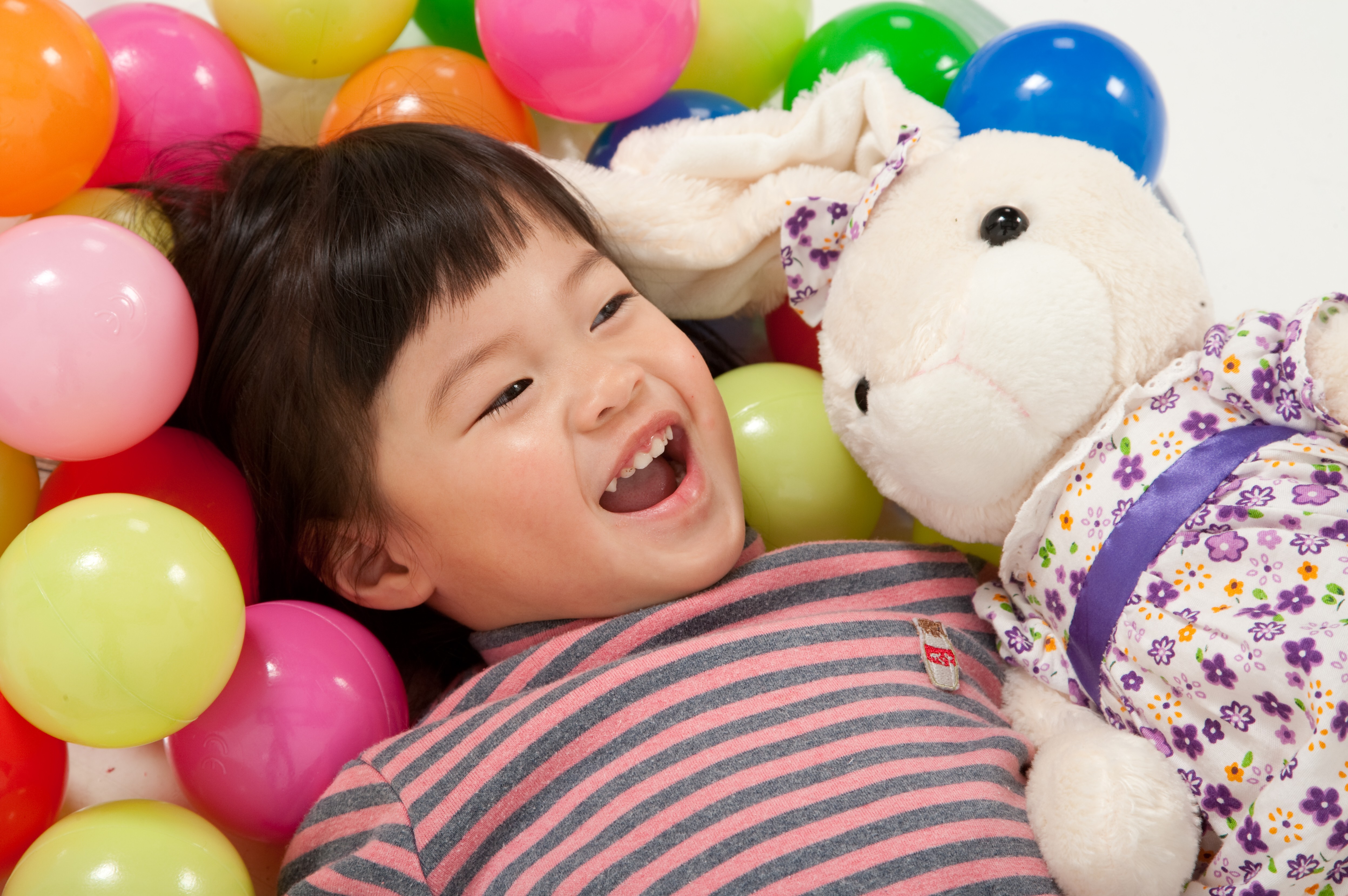 Asian little girl laughing with rabbit cuddly toy