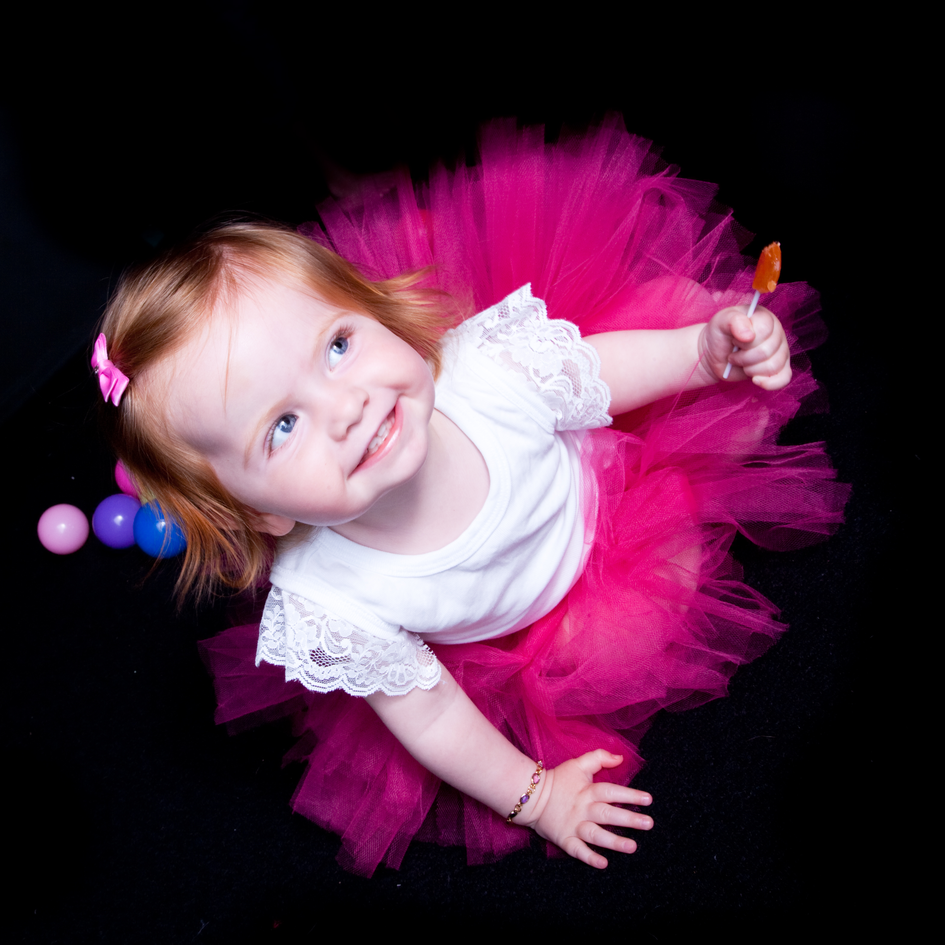 Pink ballerina dress on toddler, Auckland, Anais Chaine Stuido black background. Do you want my candy?
