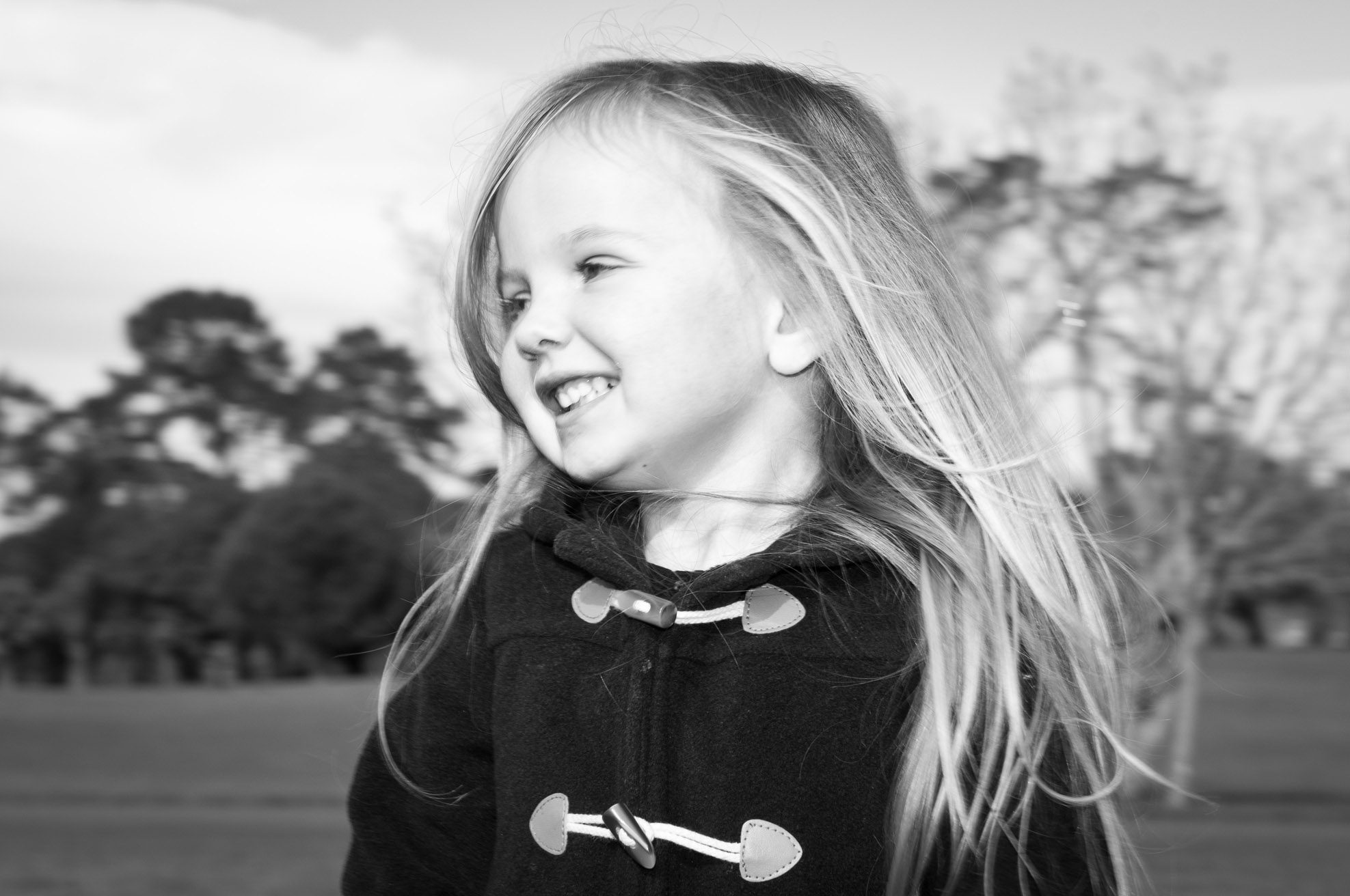 Professional portrait of young girl smiling in movement black and white in One Tree hill Park, Auckland, New Zealand