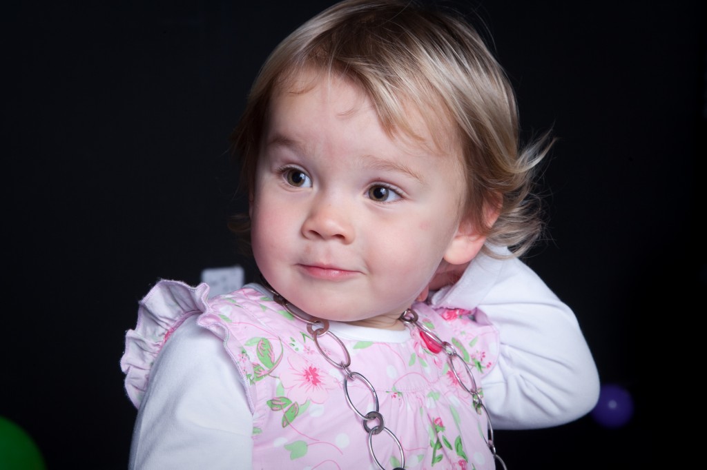 Baby girl toddler with pink dress acting like a star. Studio photoshoot with black background.